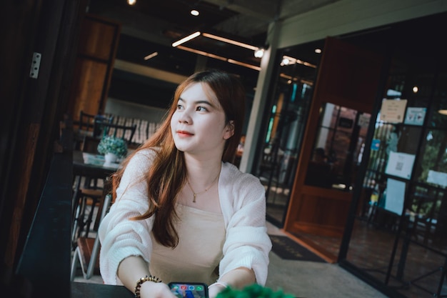 Retrato de uma jovem mulher olhando para longe enquanto estava sentada em um café
