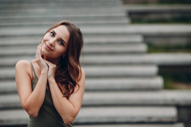 Retrato de uma jovem mulher positiva com cabelo castanho, tocando o rosto