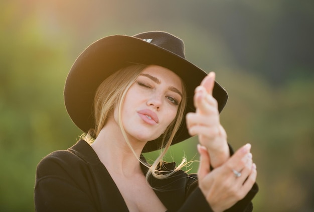 Retrato de uma jovem mulher romântica ao ar livre com rosto de beleza mão feminina em gesto de arma