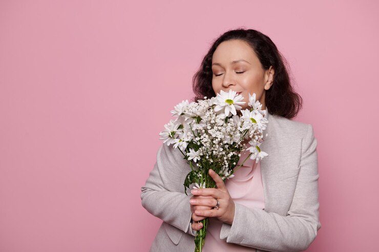 Foto retrato de uma jovem mulher segurando um buquê contra um fundo rosa