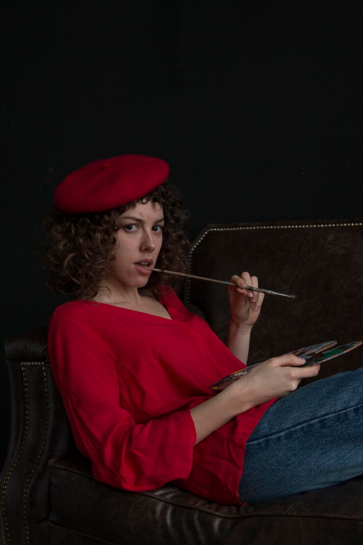 Foto retrato de uma jovem mulher segurando uma paleta e um pincel enquanto estava sentada no sofá