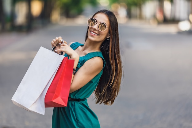 Retrato de uma jovem mulher sorridente feliz com sacos de compras, desfrutando de compras. Emoções positivas.