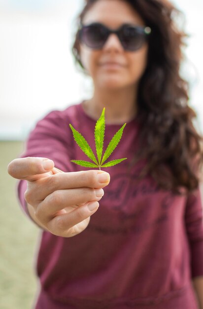 Foto retrato de uma jovem mulher usando óculos de sol de pé contra plantas