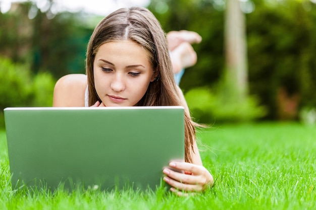 Retrato de uma jovem mulher usando seu laptop em um parque