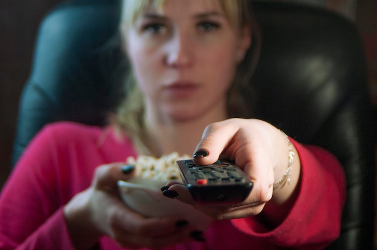 Foto retrato de uma jovem mulher vendo televisão sentada em uma cadeira
