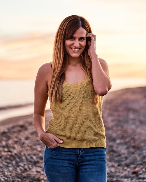 Foto retrato de uma jovem na praia ao pôr do sol