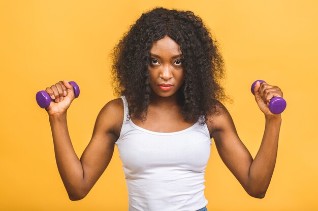 Retrato de uma jovem negra afro-americana exercitando seus músculos com halteres