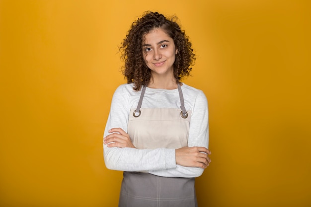 Retrato de uma jovem negra bonita no avental. menina afro de sorriso no estúdio no fundo amarelo.