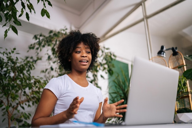 Retrato de uma jovem negra sentada à mesa por laptop aprender sobre conversa à distância falar responder perguntas na consulta virtual