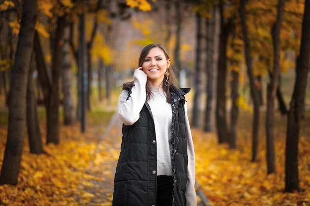 Retrato de uma jovem no parque de outono de Almaty no beco com folhas de outono caídas