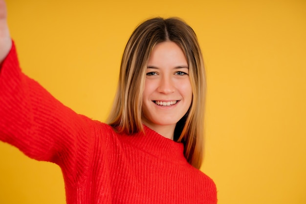 Foto retrato de uma jovem olhando para a câmera e sorrindo enquanto tirava uma selfie no estúdio.