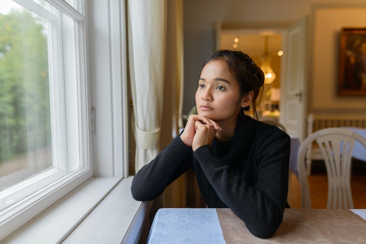 Foto retrato de uma jovem olhando para longe enquanto está sentada na mesa