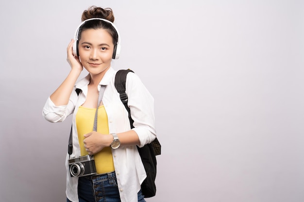 Retrato de uma jovem ouvindo música através de fones de ouvido enquanto está de pé contra um fundo branco