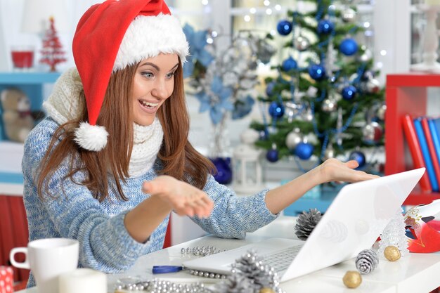 Retrato de uma jovem pensativa usando laptop se preparando para o Natal