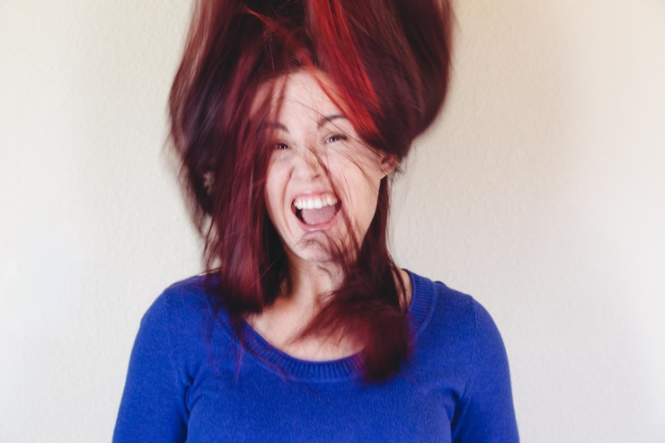 Foto retrato de uma jovem rindo com o cabelo desarranjado contra a parede