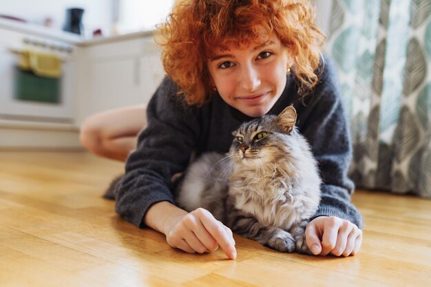 Retrato de uma jovem ruiva e encaracolada com um amado gato doméstico fofinho