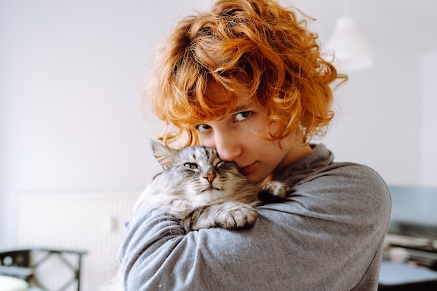 Retrato de uma jovem ruiva e encaracolada com um amado gato doméstico fofinho