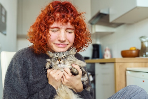 Foto retrato de uma jovem ruiva e encaracolada com um amado gato doméstico fofinho