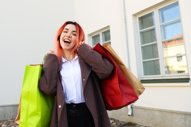 Retrato de uma jovem ruiva segurando sacolas depois de fazer compras