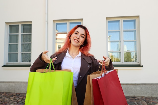 Foto retrato de uma jovem ruiva segurando sacolas depois de fazer compras