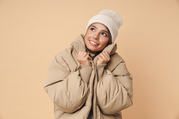 Foto retrato de uma jovem satisfeita com um casaco de inverno sorrindo e olhando para cima