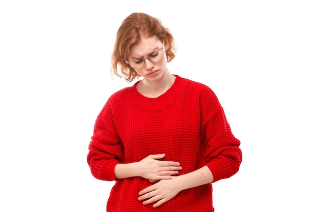 Retrato de uma jovem segurando as mãos no estômago sofrendo de dores menstruais e desconforto intestinal isolado em fundo branco