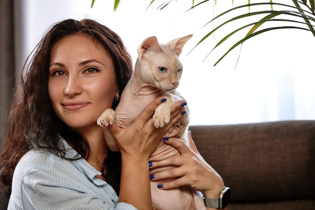 Retrato de uma jovem segurando um gato fofo de olhos azuis fêmea abraçando seu lindo gatinho de cabelo curto espaço de cópia de fundo fechado conceito adorável de animal de estimação doméstico