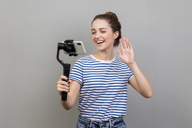 Foto retrato de uma jovem segurando uma câmera contra a parede