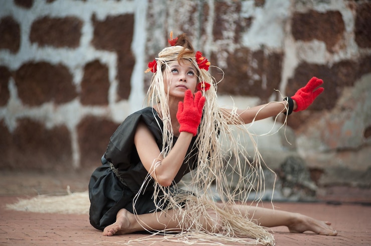 Foto retrato de uma jovem sentada contra a parede vermelha