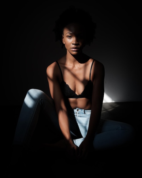 Retrato de uma jovem sentada em uma sala escura