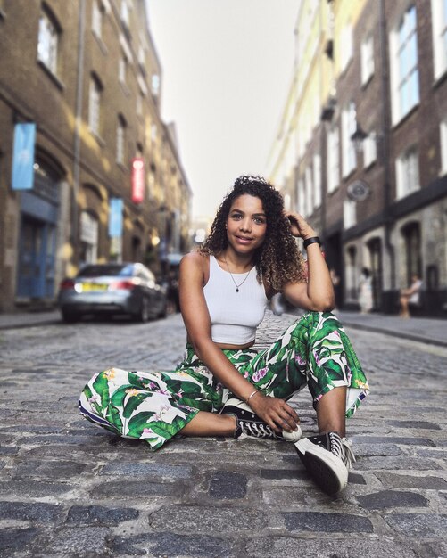 Foto retrato de uma jovem sentada na rua da cidade