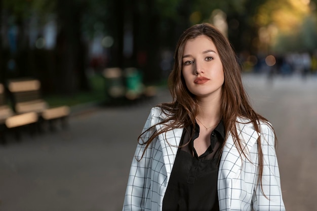 Retrato de uma jovem séria com cabelos longos e maquiagem diurna Atraente menina morena olha para a câmera