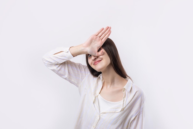 Retrato de uma jovem séria mostrando gesto de parada com a palma da mão sobre fundo branco