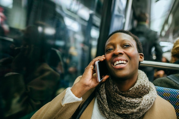 Retrato de uma jovem sorridente ao telefone no trem subterrâneo