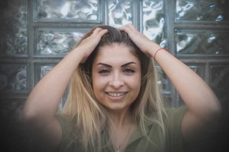 Foto retrato de uma jovem sorridente com a mão no cabelo contra a parede