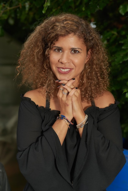 Foto retrato de uma jovem sorridente com as mãos apertadas