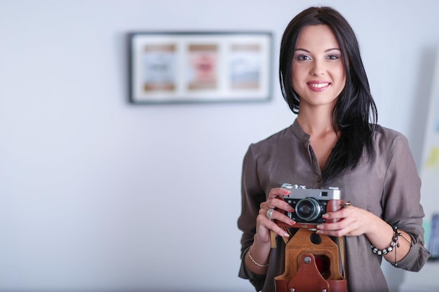 Retrato de uma jovem sorridente com câmera sentada no apartamento loft