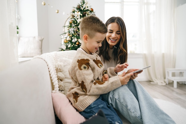 Retrato de uma jovem sorridente com seu filho usando tablet digital nas férias de inverno