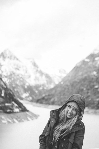 Foto retrato de uma jovem sorridente contra o lago e as montanhas durante o inverno