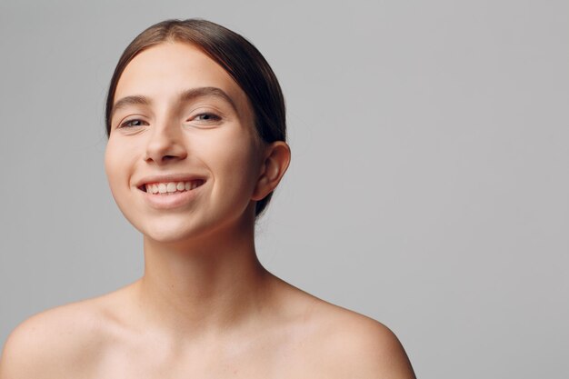 Foto retrato de uma jovem sorridente contra um fundo cinzento