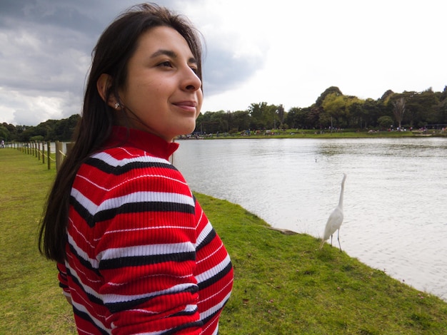 Foto retrato de uma jovem sorridente de pé ao lado do lago contra o céu