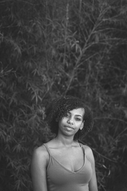 Foto retrato de uma jovem sorridente de pé contra as plantas