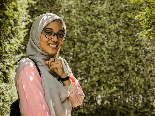 Foto retrato de uma jovem sorridente de pé contra as plantas