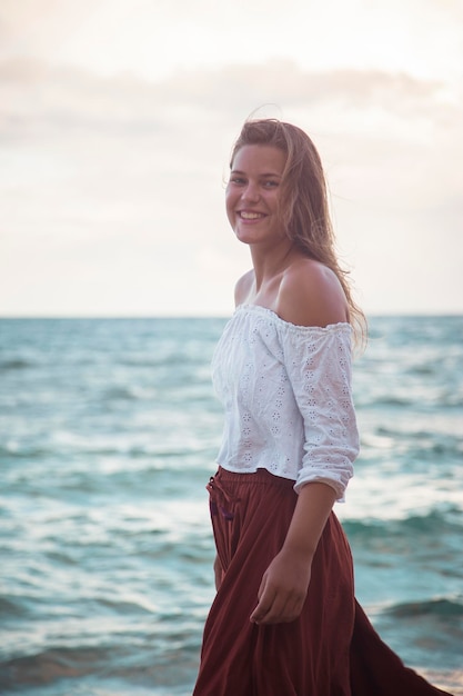 Retrato de uma jovem sorridente de pé na praia