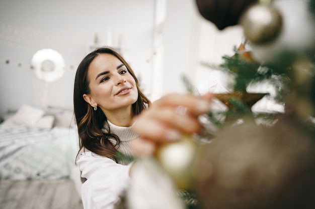 Retrato de uma jovem sorridente decorando uma árvore de Natal