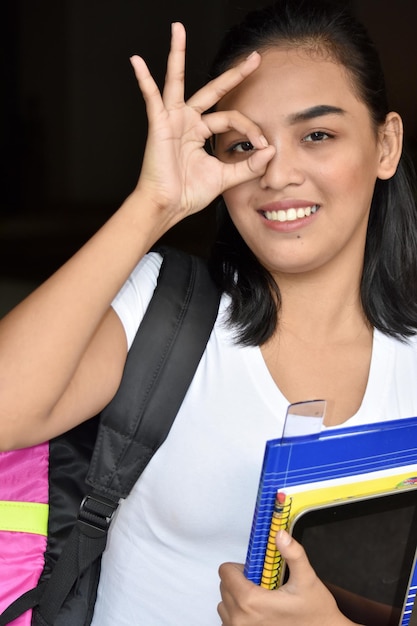 Foto retrato de uma jovem sorridente fazendo gestos enquanto segura livros e tablet digital