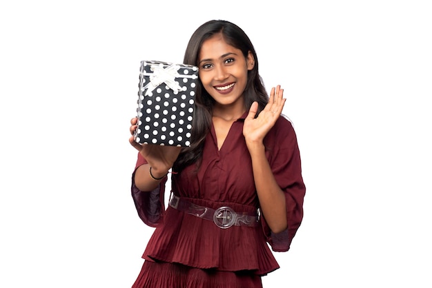 Retrato de uma jovem sorridente feliz de vestido vermelho segurando e posando com caixa de presente em fundo branco