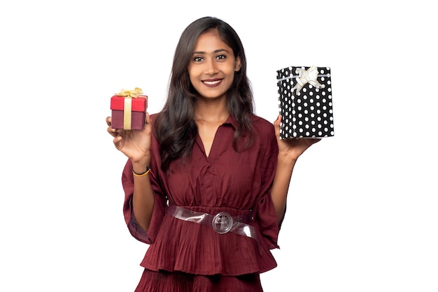 Retrato de uma jovem sorridente feliz de vestido vermelho segurando e posando com caixa de presente em fundo branco