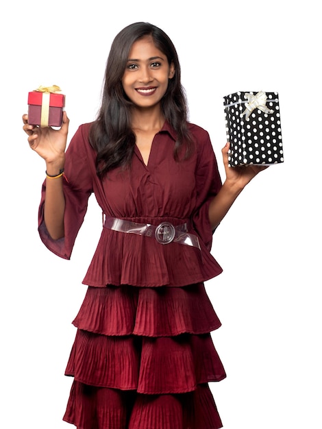 Retrato de uma jovem sorridente feliz de vestido vermelho segurando e posando com caixa de presente em fundo branco