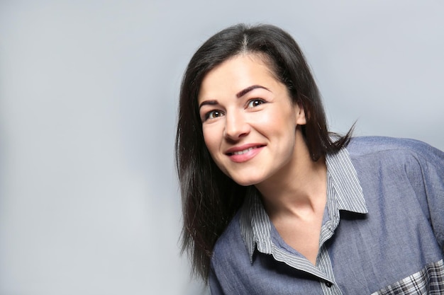 Retrato de uma jovem sorridente feliz em fundo cinza